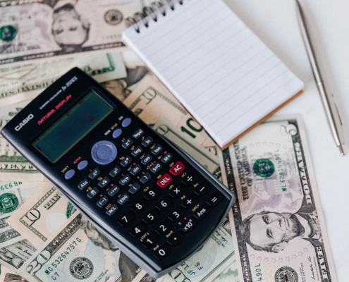 Calculator and notepad placed on usa dollars stack