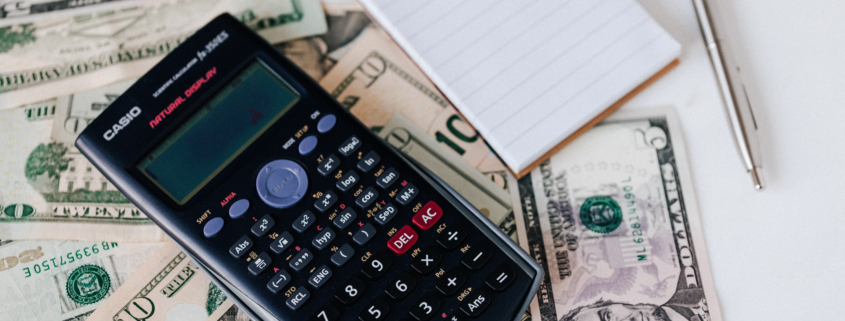 Calculator and notepad placed on usa dollars stack